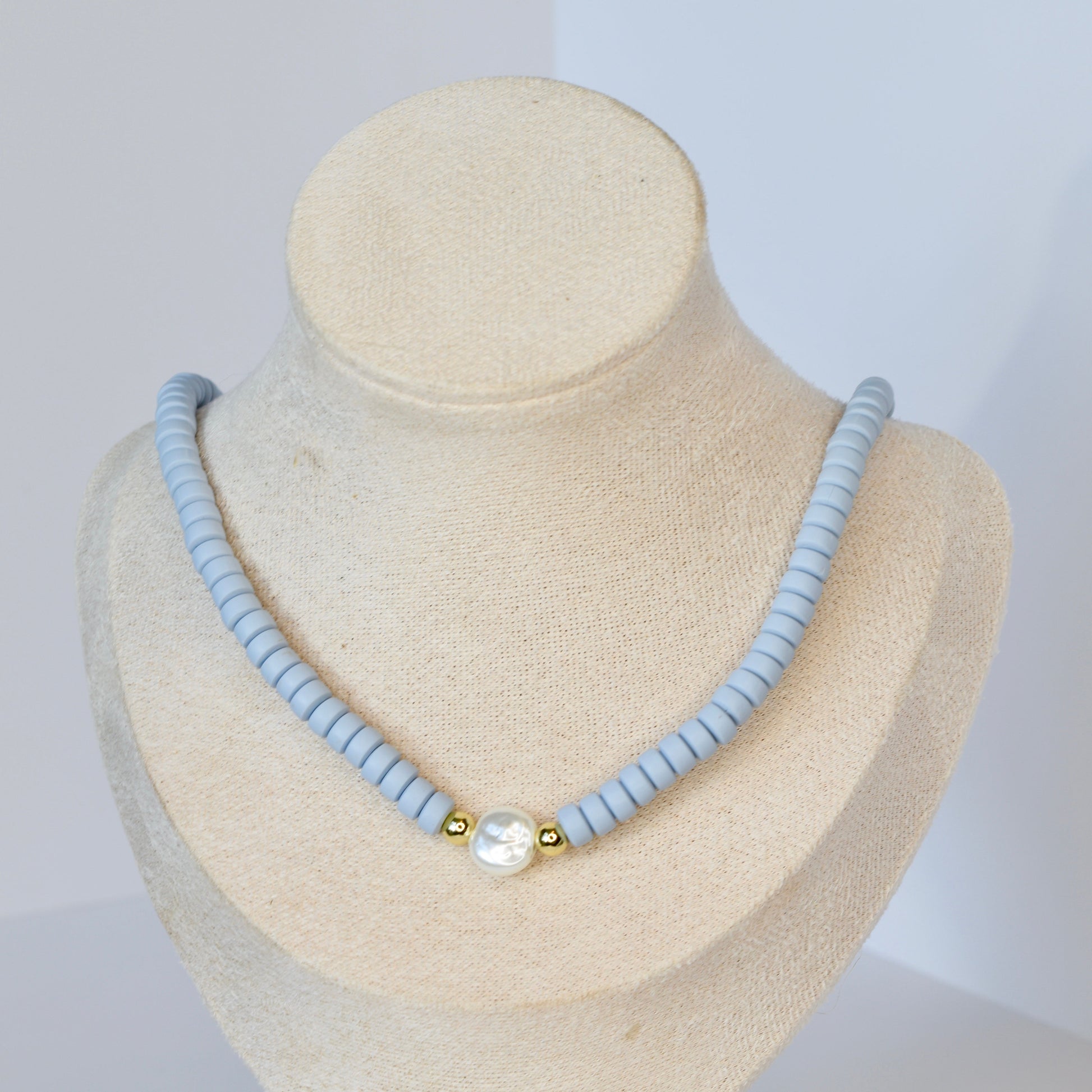 Necklace with light blue beads on a mannequin bust against a white background